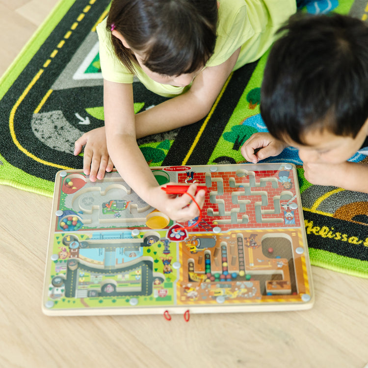 A kid playing with The Melissa & Doug PAW Patrol Wooden 4-in-1 Magnetic Wand Maze Board