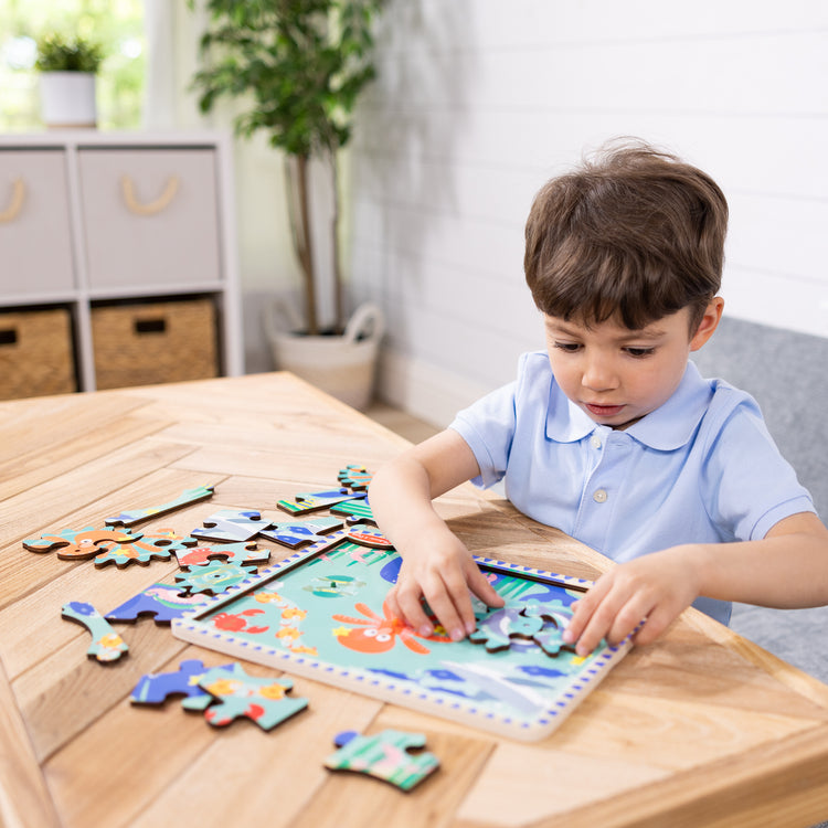 A kid playing with The Melissa & Doug Wooden Underwater Jigsaw Spinning Gear Puzzle – 18 Pieces