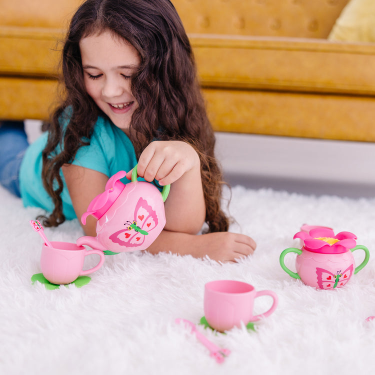 A kid playing with The Melissa & Doug Butterfly Tea Set (15 pcs) - Play Food Accessories