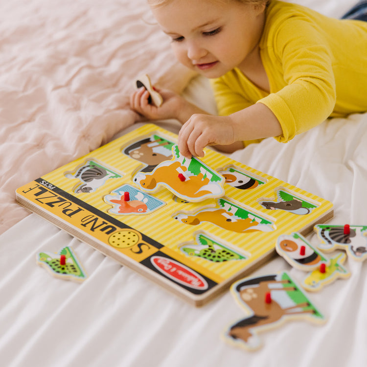 A kid playing with The Melissa & Doug Pets Sound Puzzle - Wooden Peg Puzzle With Sound Effects (8 pcs)