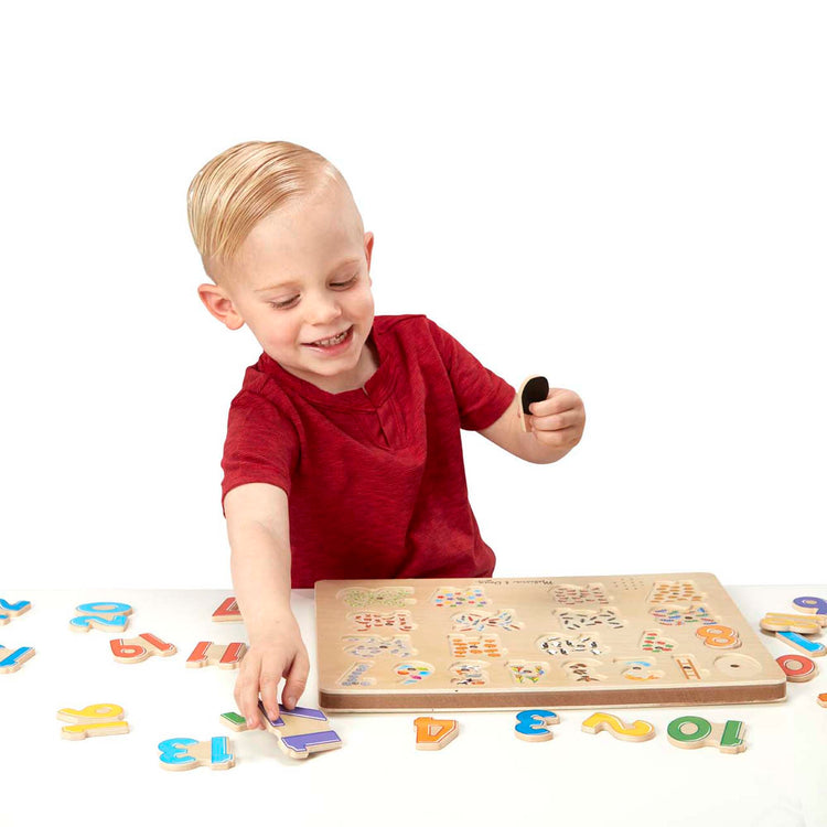 A child on white background with The Melissa & Doug Numbers Sound Puzzle - Wooden Puzzle With Sound Effects (21 pcs)