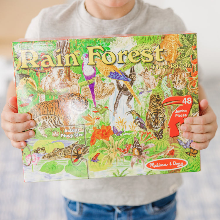 A kid playing with The Melissa & Doug Rainforest Floor Puzzle (48 pcs, 2 x 3 feet)
