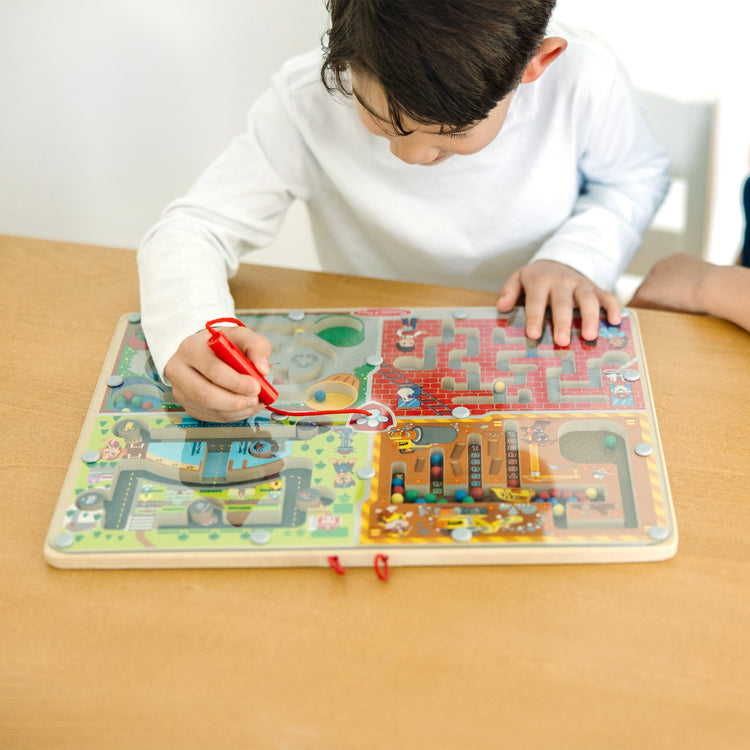 A kid playing with The Melissa & Doug PAW Patrol Wooden 4-in-1 Magnetic Wand Maze Board