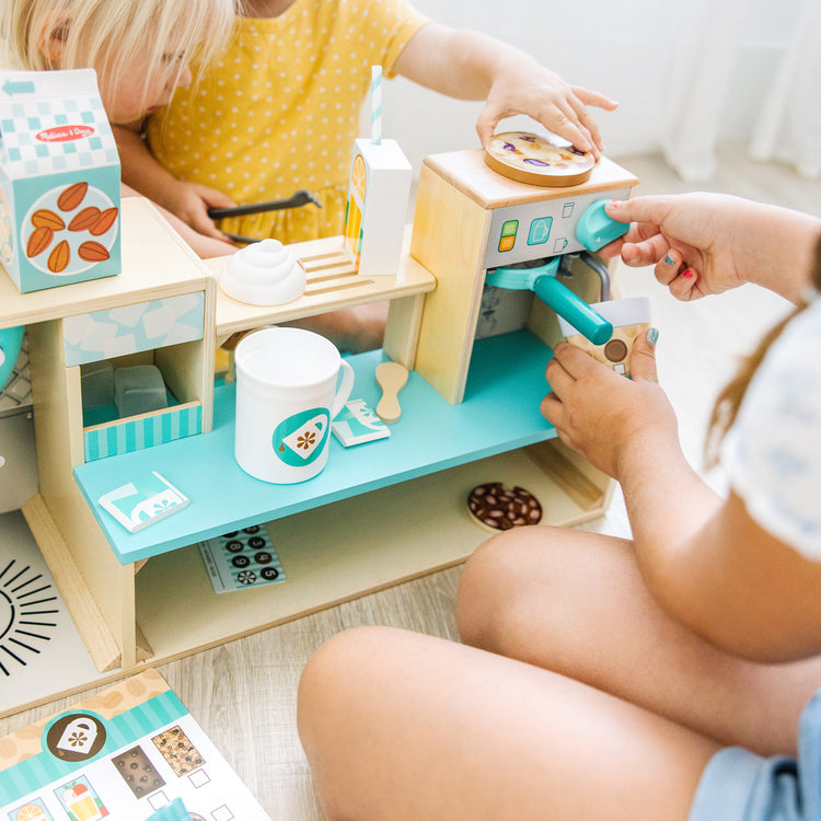 A kid playing with The Melissa & Doug Wooden Café Barista Coffee Shop (35 Pieces)