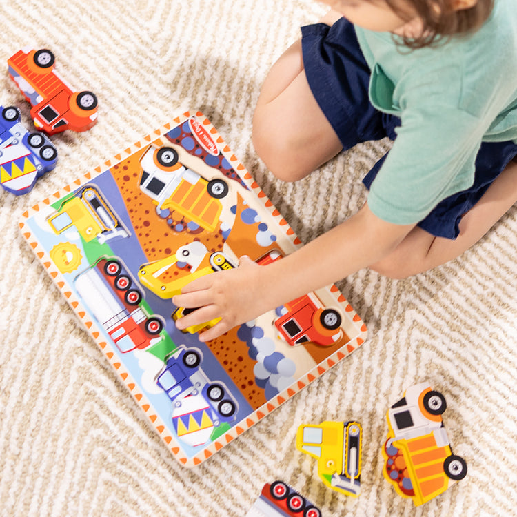 A kid playing with The Melissa & Doug Construction Vehicles Wooden Chunky Puzzle (6 pcs)