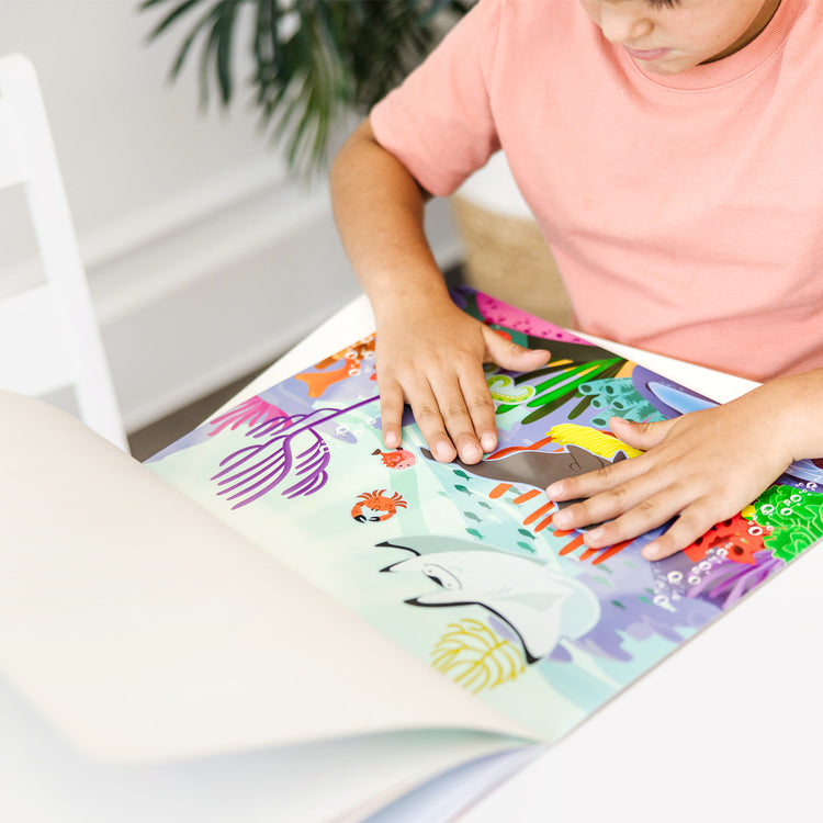 A kid playing with The Melissa & Doug Reusable Sticker Activity Pad - Under The Sea