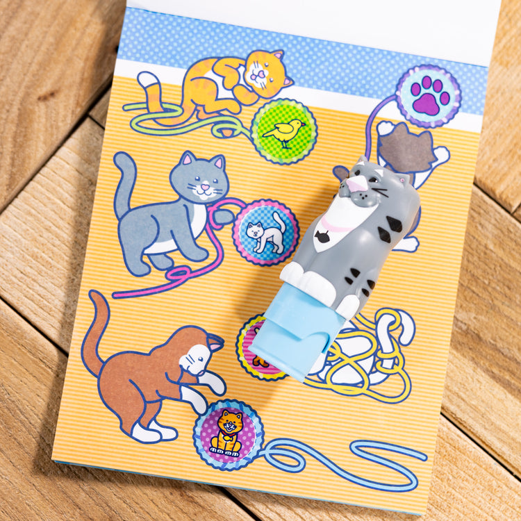 A playroom scene with The Melissa & Doug Sticker WOW!™ 24-Page Activity Pad and Sticker Stamper, 300 Stickers, Arts and Crafts Fidget Toy Collectible Character – Cat