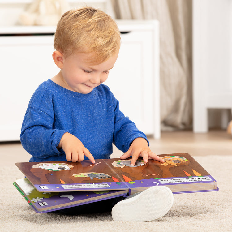 A kid playing with The Melissa & Doug Children's Book - Poke-a-Dot: Goodnight, Animals (Board Book with Buttons to Pop)