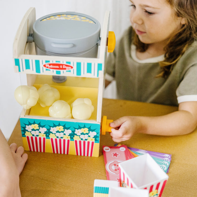 A kid playing with The Melissa & Doug Fun at the Fair! Wooden Popcorn Popping Play Food Set