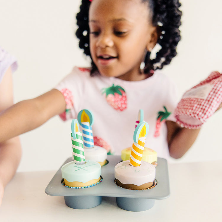 A kid playing with The Melissa & Doug Bake and Decorate Wooden Cupcake Play Food Set
