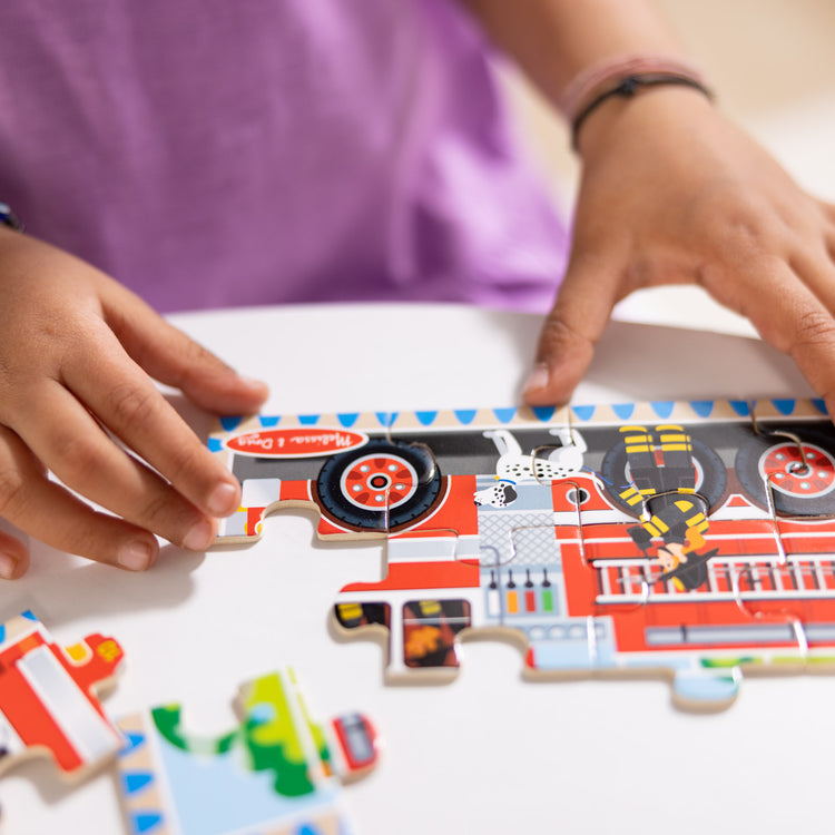 A kid playing with The Melissa & Doug Vehicles 4-in-1 Wooden Jigsaw Puzzles in a Storage Box (48 pcs)