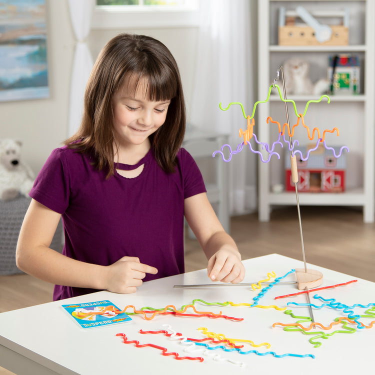A kid playing with The Melissa & Doug Suspend Junior Family Game (31 pcs)