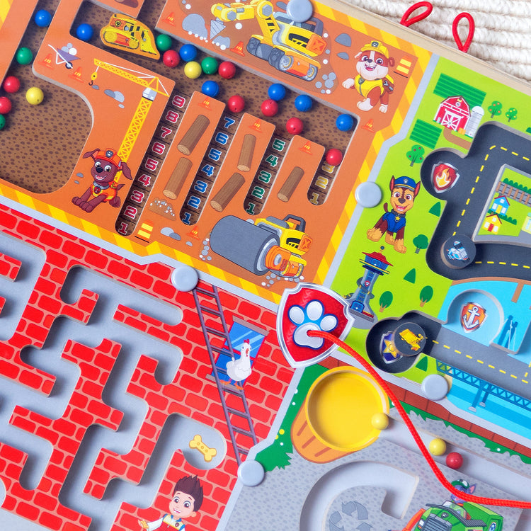 The loose pieces of The Melissa & Doug PAW Patrol Wooden 4-in-1 Magnetic Wand Maze Board
