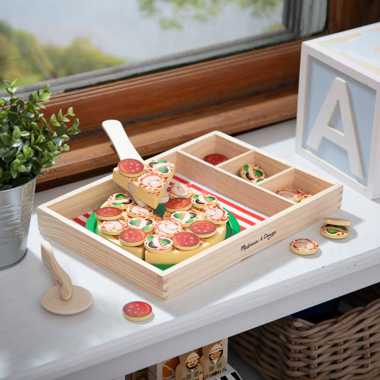 A playroom scene with The Melissa & Doug Wooden Pizza Party Play Food Set With 36 Toppings