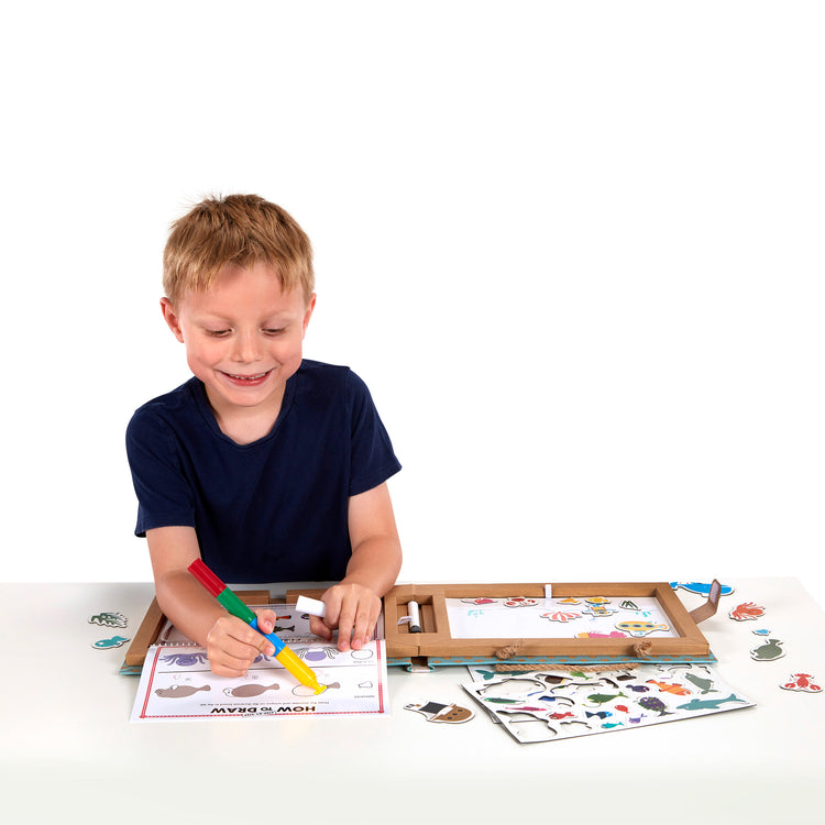 A child on white background with The Melissa & Doug Natural Play: Play, Draw, Create Reusable Drawing & Magnet Kit – Ocean (42 Magnets, 5 Dry-Erase Markers)