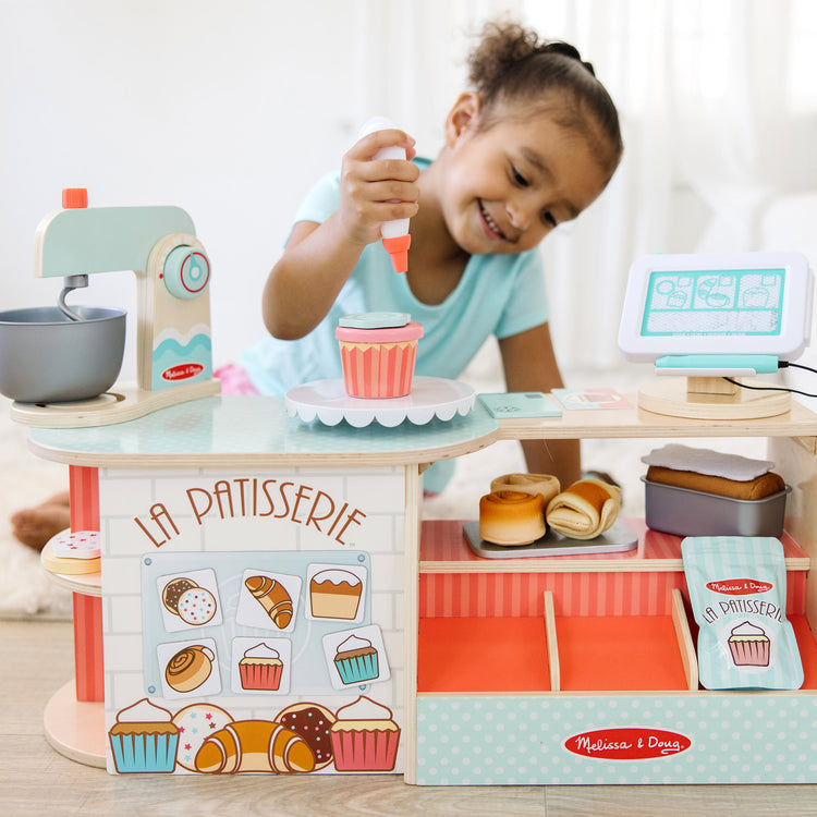 A kid playing with The Melissa & Doug Wooden La Patisserie Bakery (39 Pieces)