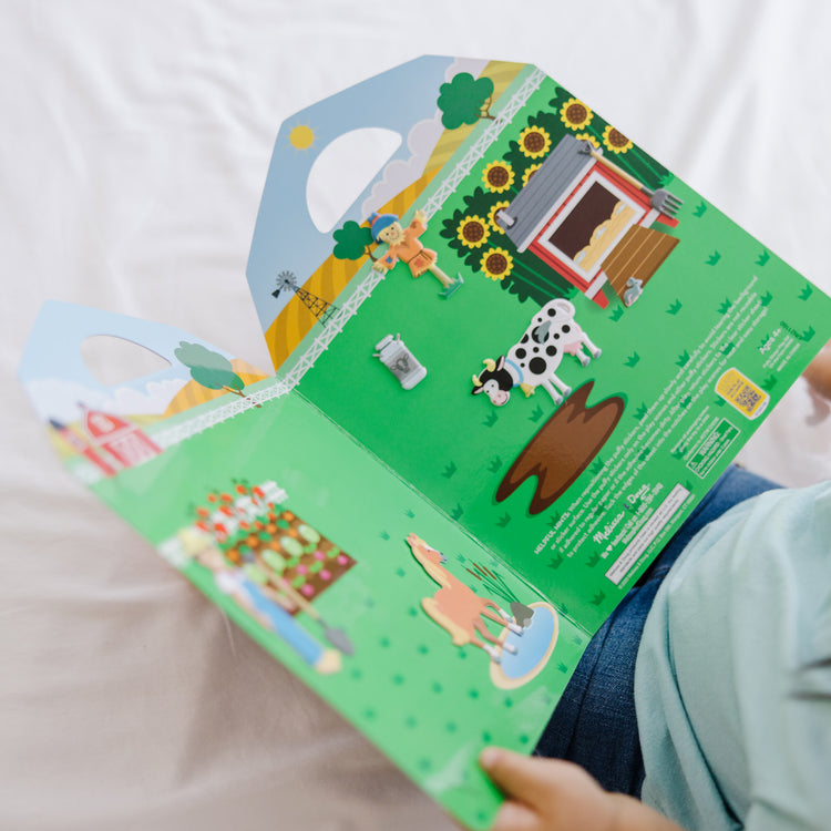 A kid playing with The Melissa & Doug Puffy Sticker Play Set - On the Farm - 52 Reusable Stickers, 2 Fold-Out Scenes