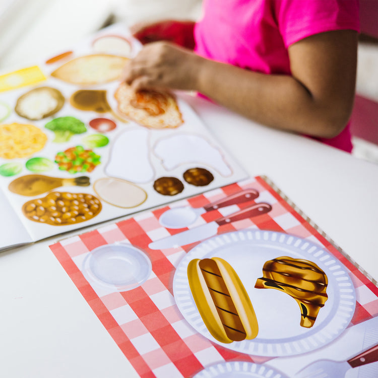 A kid playing with The Melissa & Doug Sticker Pads 3-Pack - Sweets and Treats, Make-a-Face Fashion, and Make-a-Meal