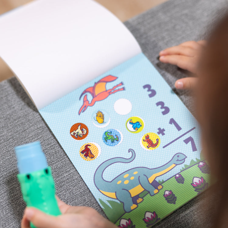 A kid playing with The Melissa & Doug Sticker WOW!™ Dinosaur and Tiger Bundle: 2 24-Page Activity Pads, 2 Sticker Stampers, 600 Stickers, Arts and Crafts Fidget Toy Collectible Characters