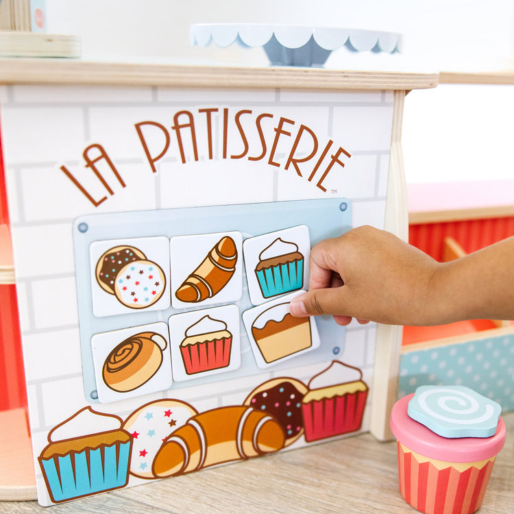 A kid playing with The Melissa & Doug Wooden La Patisserie Bakery (39 Pieces)