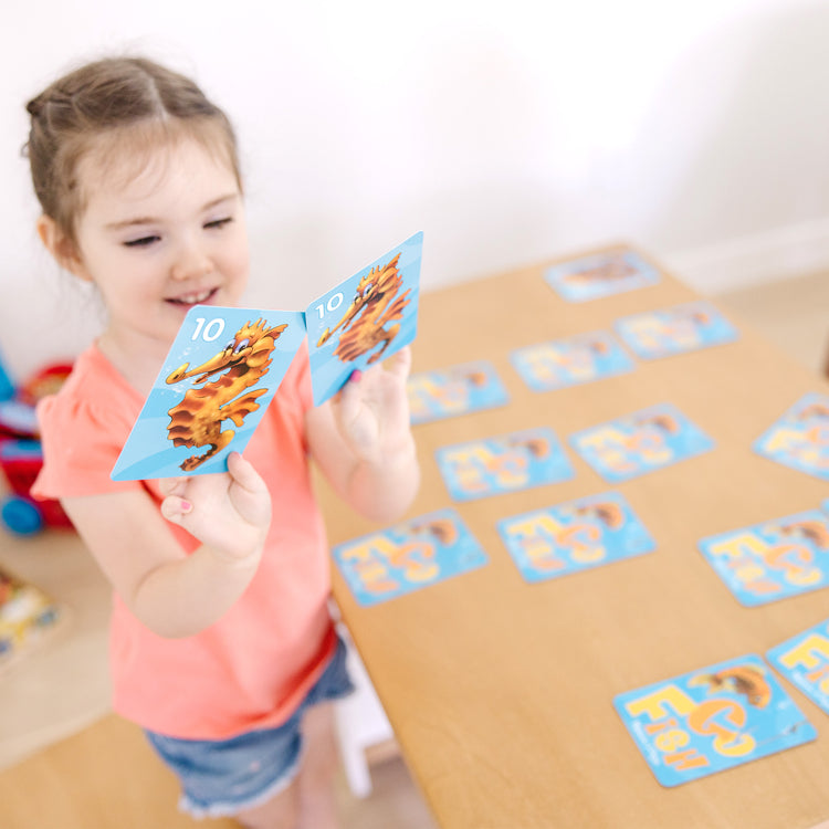 A kid playing with The Melissa & Doug Classic Card Games Set - Old Maid, Go Fish, Rummy