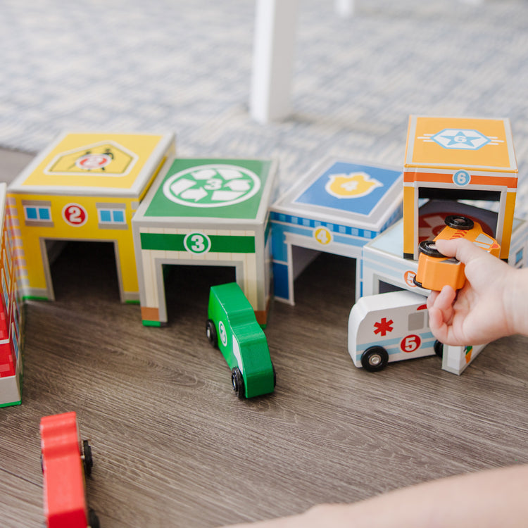 A kid playing with The Melissa & Doug Nesting and Sorting Blocks - 6 Buildings, 6 Wooden Vehicles