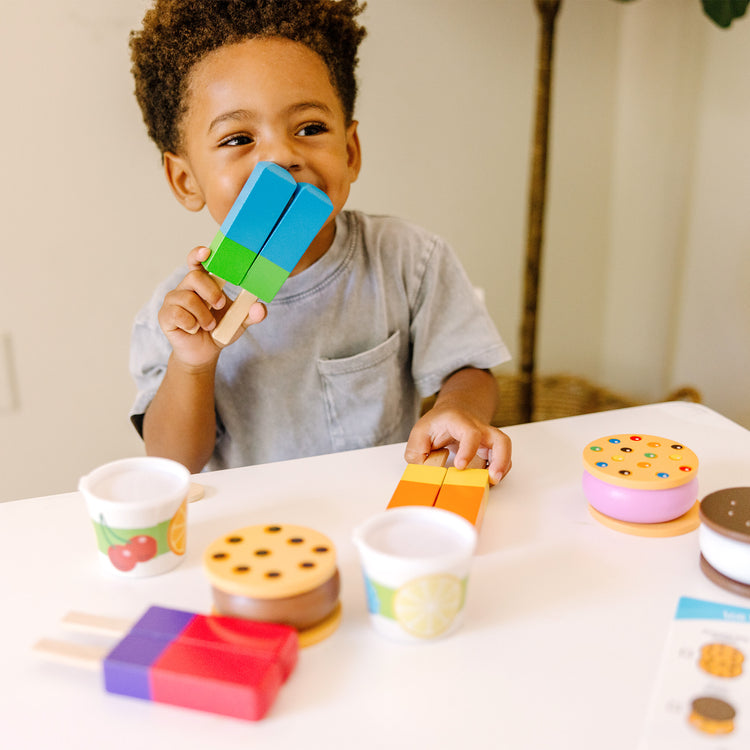 A kid playing with The Melissa & Doug Wooden Frozen Treats Ice Cream Play Set (24 pcs) - Play Food and Accessories