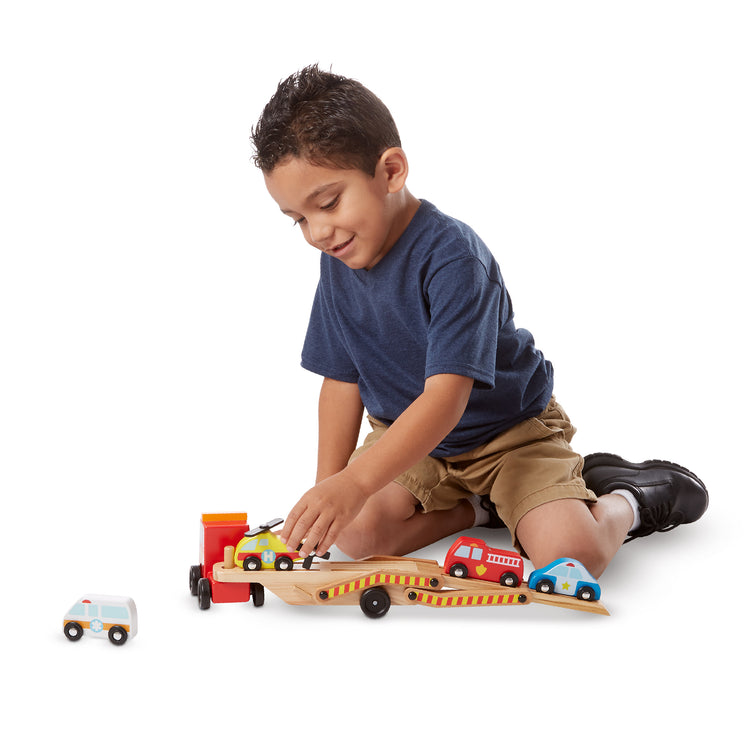 A child on white background with The Melissa & Doug Wooden Emergency Vehicle Carrier Truck With 1 Truck and 4 Rescue Vehicles