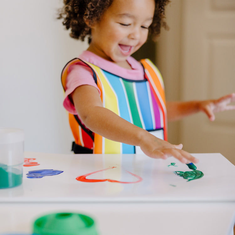 A kid playing with The Melissa & Doug Finger Paint Paper Pad (12 x 18 inches) - 50 Sheets, 2-Pack