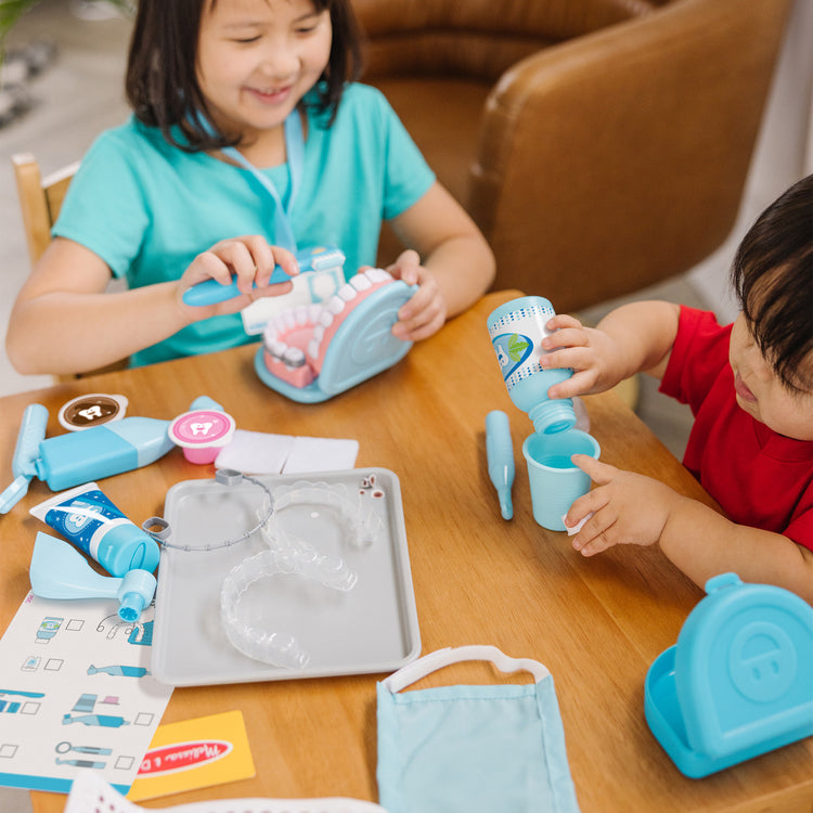 A kid playing with The Melissa & Doug Super Smile Dentist Kit With Pretend Play Set of Teeth And Dental Accessories (25 Toy Pieces)