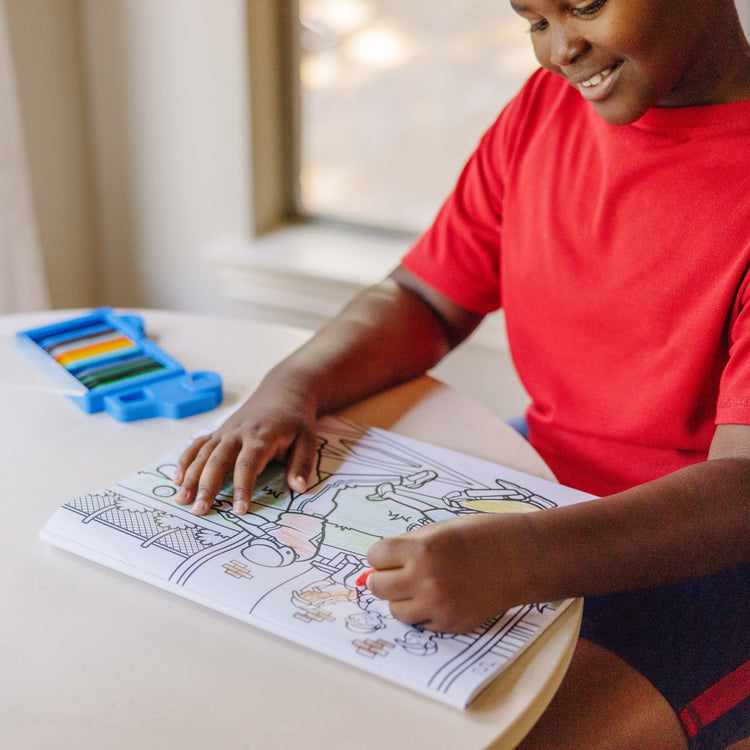 A kid playing with The Melissa & Doug Jumbo 50-Page Kids' Coloring Pad - Space, Sharks, Sports, and More
