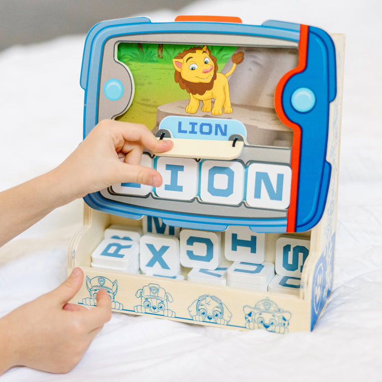 A kid playing with The Melissa & Doug PAW Patrol Wooden See & Spell Pup Pad Game