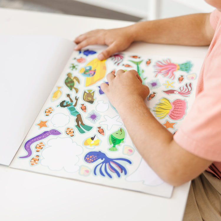 A kid playing with The Melissa & Doug Reusable Sticker Activity Pad - Under The Sea