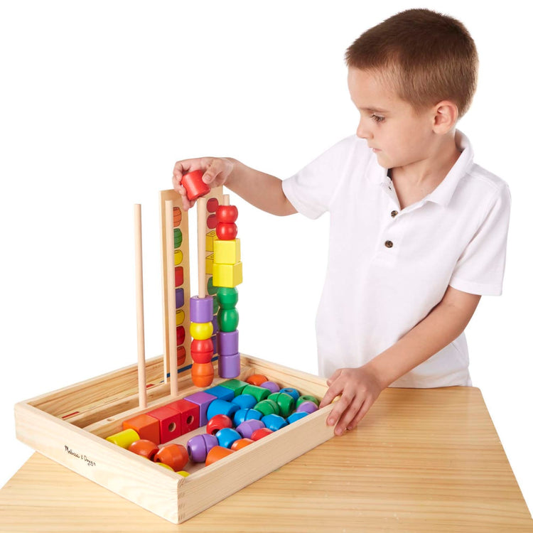 A child on white background with the Melissa & Doug Bead Sequencing Set With 46 Wooden Beads and 5 Double-Sided Pattern Boards