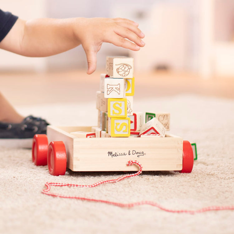 A kid playing with the Melissa & Doug Classic ABC Wooden Block Cart Educational Toy With 30 1-Inch Solid Wood Blocks