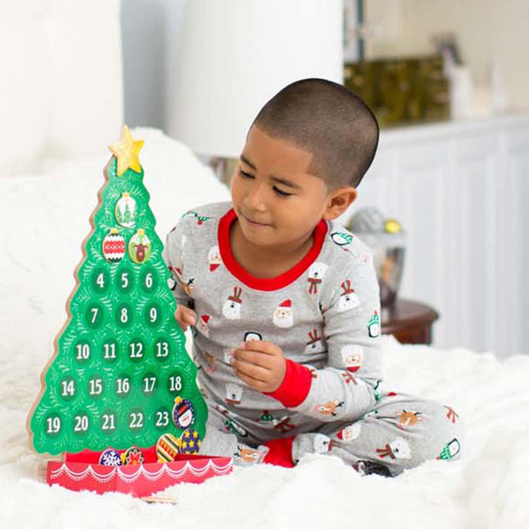 A kid playing with the Melissa & Doug Countdown to Christmas Wooden Advent Calendar - Magnetic Tree, 25 Magnets