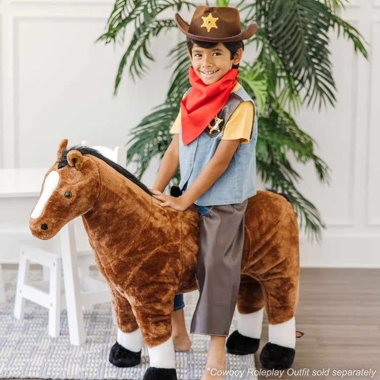 A kid playing with the Melissa & Doug Cowboy Role Play Costume Set (5 pcs) - Includes Faux Leather Chaps