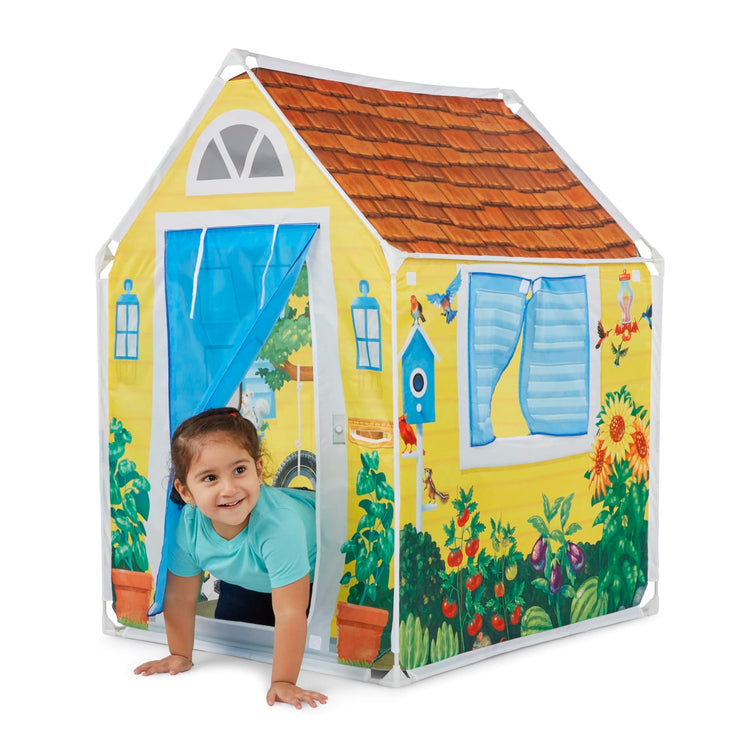 A child on white background with the Melissa & Doug Cozy Cottage Fabric Play Tent and Storage Tote