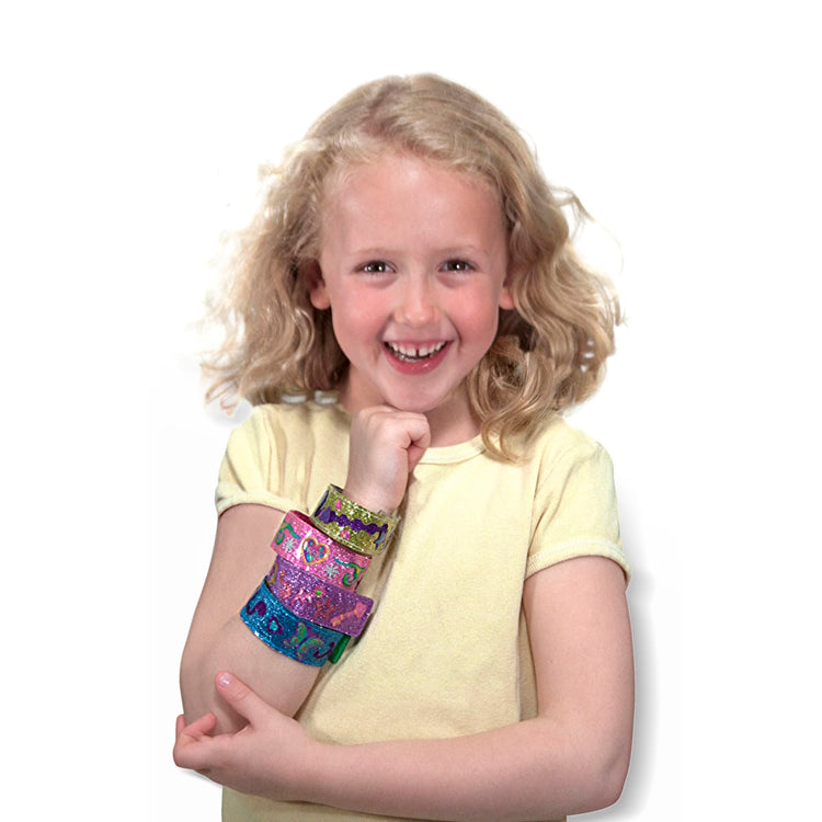 A child on white background with the Melissa & Doug Design-Your-Own Bracelets With 100+ Sparkle Gem and Glitter Stickers