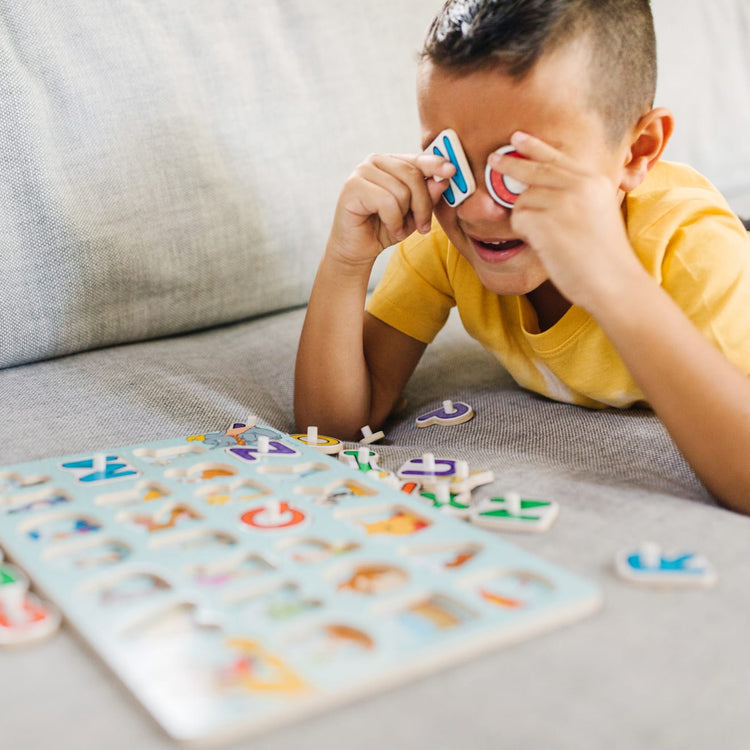 A kid playing with the Melissa & Doug Disney Classics Alphabet Wooden Peg Puzzle (26 pcs)