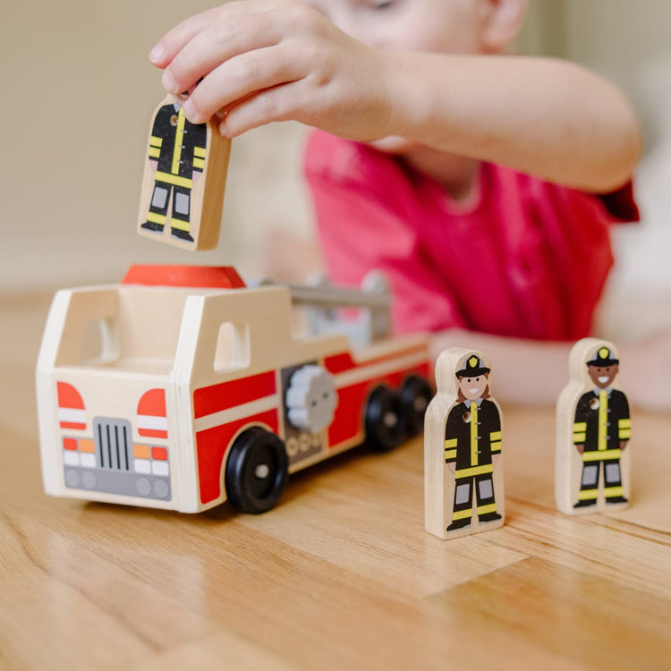 A kid playing with the Melissa & Doug Wooden Fire Truck With 3 Firefighter Play Figures