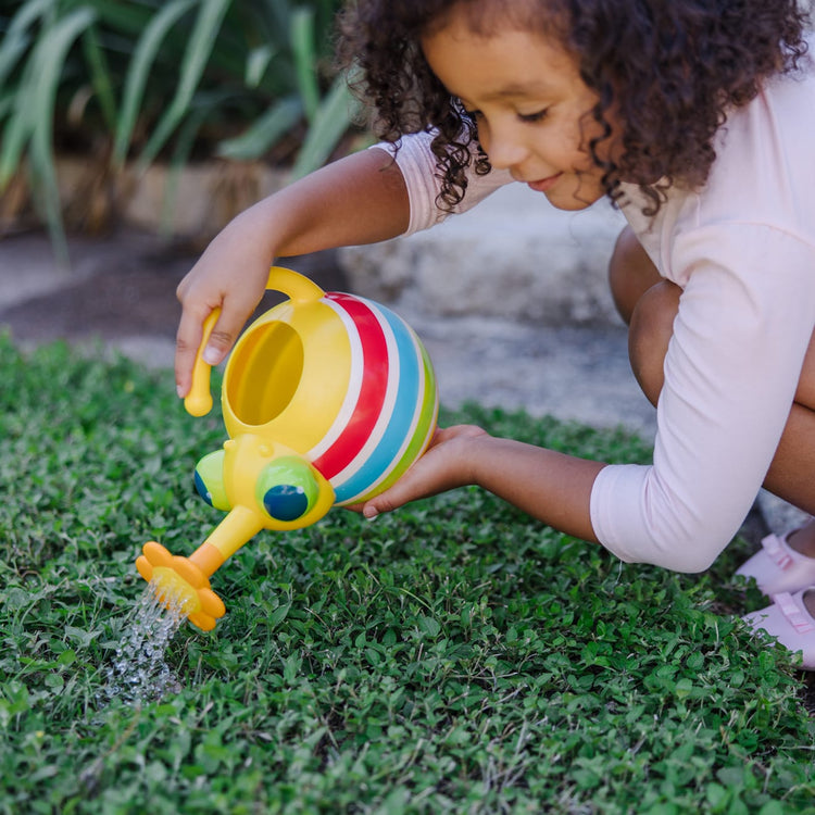A kid playing with the Melissa & Doug Sunny Patch Giddy Buggy Watering Can With Flower-Shaped Spout