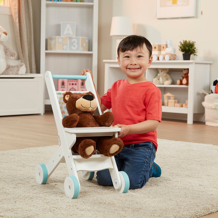 A kid playing with the Melissa & Doug Mine to Love Wooden Play Stroller for Dolls, Stuffed Animals - White (18”H x 8”W x 11”D Assembled)