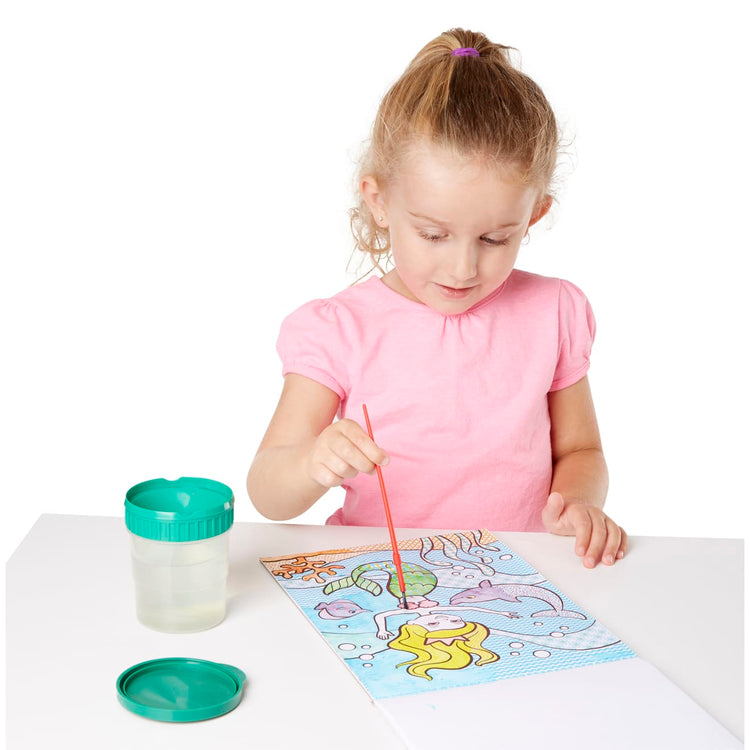 A child on white background with the Melissa & Doug My First Paint With Water Art Pad - Cheerleaders, Flowers, Fairies, and More (24 Pages)