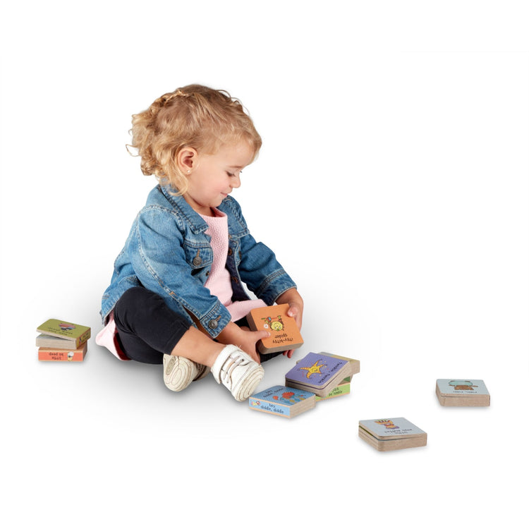 A child on white background with the Melissa & Doug Children's Book - Natural Play Book Tower: Little Nursery Books