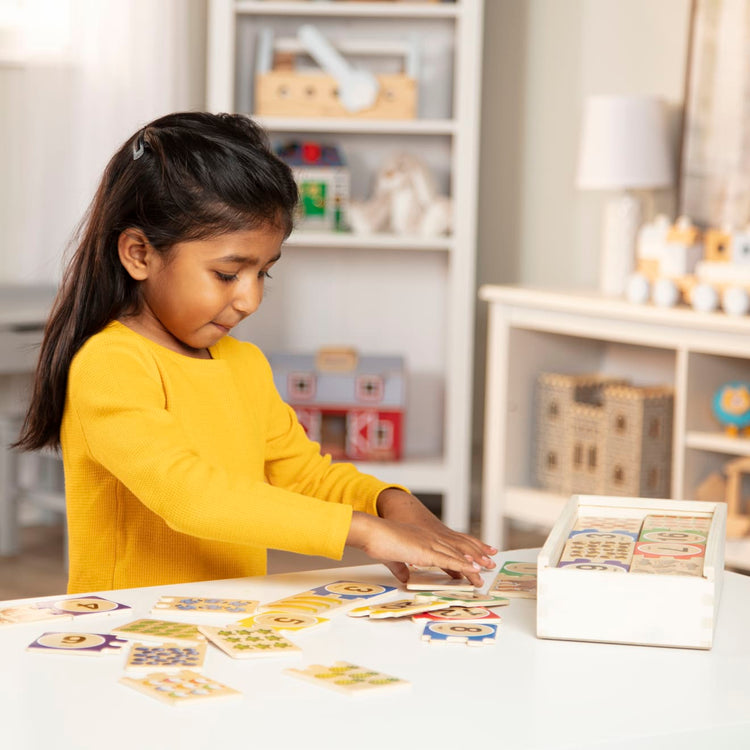 A kid playing with the Melissa & Doug Self-Correcting Wooden Number Puzzles With Storage Box (40 pcs)