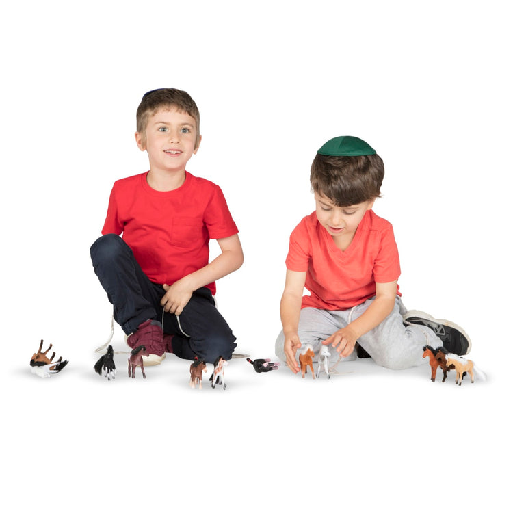 A child on white background with the Melissa & Doug Pasture Pals - 12 Collectible Horses With Wooden Barn-Shaped Crate