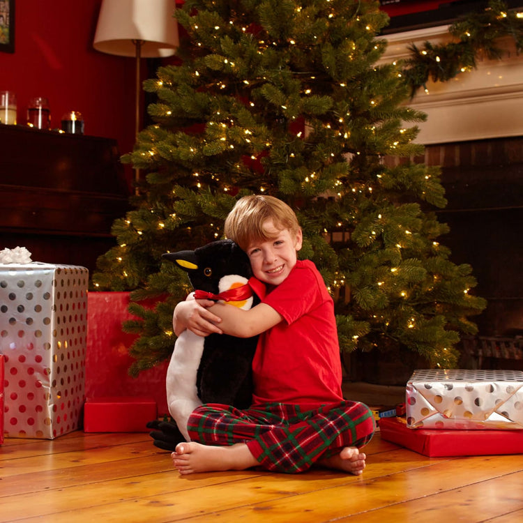 A kid playing with the Melissa & Doug Giant Penguin - Lifelike Stuffed Animal (nearly 2 feet tall)