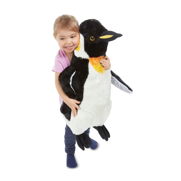 A child on white background with the Melissa & Doug Giant Penguin - Lifelike Stuffed Animal (nearly 2 feet tall)