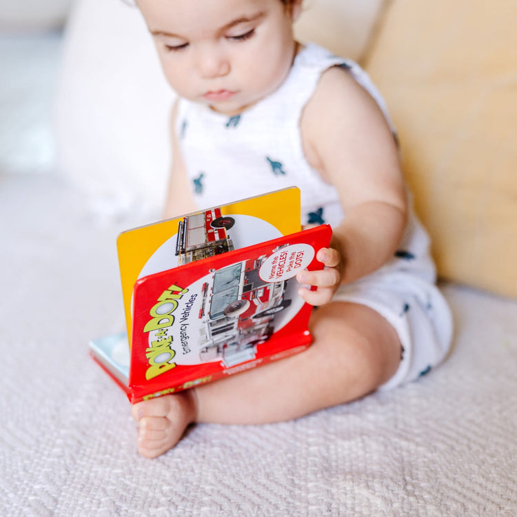 A kid playing with the Melissa & Doug Children’s Book – Poke-a-Dot: Emergency Vehicles (Board Book with Buttons to Pop)